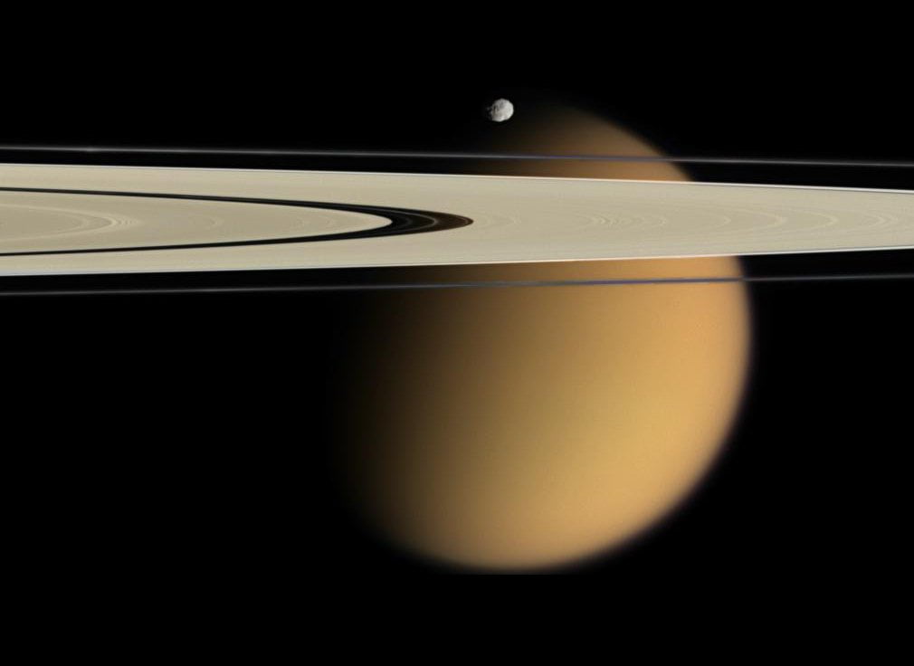 Titán, asomándose tras los anillos de Saturno, con Epimeteo por encima (NASA).